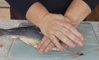 Binubuksan namin ang bangkay, ilagay ang panloob na ibabaw sa isang cutting board at pindutin ito sa itaas gamit ang aming mga kamay. Pinindot namin ang bigat ng aming mga kamay sa buong lugar ng isda. Ang tunog ng crunching buto ay maririnig - ito ay gawing mas madali upang paghiwalayin ang pulp.