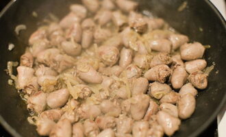 Place the prepared hearts on top of the onions. Fry for about 7 minutes until the product completely changes color.