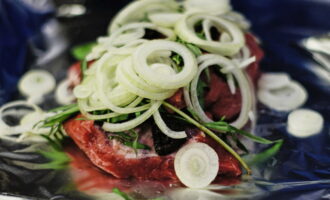 Place several layers of foil on the bottom of the pan in which you will bake the meat. Then add the beef. Peel the onions and cut into rings. Wash tarragon, mint and prunes and dry. Place herbs, prunes and onions on the meat.