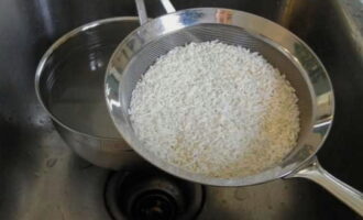 Coloque el arroz en un colador fino y enjuáguelo un par de veces con agua fría. 