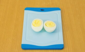 Cool the boiled eggs, peel and cut in half.