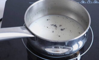 Let's move on to preparing the last mousse. Soak gelatin in cold water. Pour milk into a saucepan and add the seeds from half a vanilla pod and the pod itself. Bring the milk to a boil and let it brew for 5-10 minutes. Then we take the vanilla pod out of the milk and bring it to a boil again.