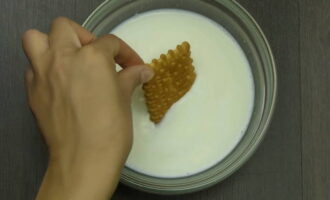 Sumerja las galletas individualmente en un recipiente aparte con leche y colóquelas en una capa una cerca de la otra en un plato aparte. 