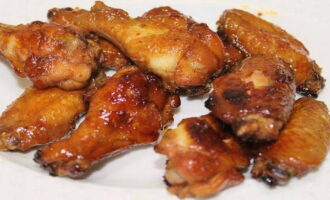 Grease the frying pan quite liberally with vegetable oil, heat it over moderate heat and lay out the chicken wings. Then add the prepared sauce and stir the wings until they are completely covered with the sauce. Fry covered, over moderate heat for 20-25 minutes. until golden brown.