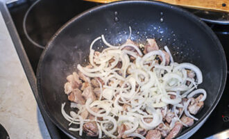 Peel the onion and cut into half rings. Add the onion to the meat in the pan, add salt and continue frying until the onion is soft.