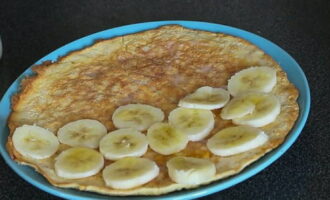 Överför den varma produkten till en platt tallrik. Lägg bananskivor på hälften av pannkakan. Täck fyllningen med den andra halvan.