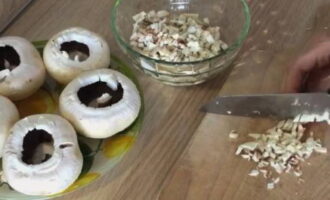 Wie lecker und einfach ist es, ganze Champignons im Ofen zu backen? Die Pilze waschen und vorsichtig mit einem Handtuch trocknen. Schneiden Sie die Beine ab. Fünf Champignons hacken und die Beine in kleine Würfel schneiden. Pflanzenöl in eine Pfanne geben, Pilze hinzufügen, mit Salz abschmecken und 10 Minuten bei schwacher Hitze braten.