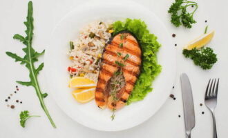 Grilled red fish steaks are served with herbs, fresh vegetables and half a lemon. Enjoy!