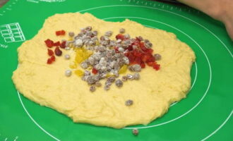 Once the dough has risen, transfer the dough to a work surface and knead it well to release all the air.Then stretch the dough into a rectangle and lay out the prepared dried fruits. Then we wrap the dough layer and form a ball.