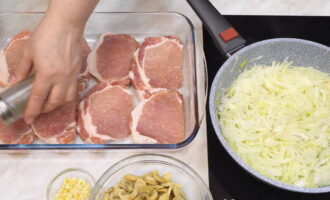 Zacznij smażyć cebulę. Wlać olej roślinny na patelnię i usmażyć cebulę. W tym czasie ułóż mięso na blasze do pieczenia lub w formie. Mięso pieprzymy i solimy do smaku.