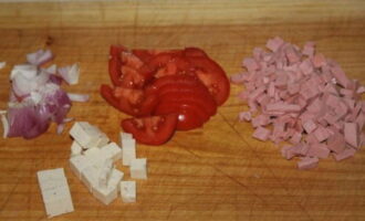 Cut the sausage and cheese into cubes, the tomato into slices, and chop the red onion.