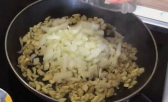 Die Zwiebel schälen, fein hacken und in die Pfanne geben. Alles vermischen und weitere 10 Minuten braten. Die mit Zwiebeln gebratenen Champignons auf einen Teller geben und etwas abkühlen lassen.