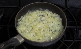 Turn on the stove and place the frying pan on the burner.Heat it together with the oil. Take the onion and peel it. Cut into small pieces. Place in a frying pan and fry until soft and golden brown.