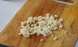 Let's start chopping the garlic. We clean the cloves from excess husk. Then cut the garlic into small pieces and add to the ketchup and mayonnaise mixture.