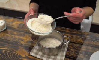 Then, without sifting the flour, add 120 grams of the total amount and mix the dough. The consistency of the dough should resemble rich sour cream. Cover the pan with a lid and leave in a warm place until the dough increases in volume.