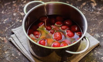 Doe de voorbereide en schone aardbeien in een pan, giet onmiddellijk hete suikersiroop en laat afkoelen tot kamertemperatuur.