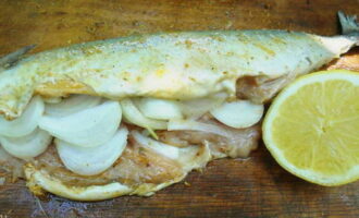 Peel and cut the onion into half rings. Place the onion inside the fish. Pour the juice of half a lemon over the carcass and leave to marinate for 30 minutes.