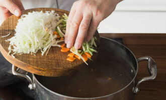 준비된 국물에 야채(당근과 셀러리)를 추가합니다. 5분 동안 요리하세요. 다음 - 양파와 양배추. 5분 더 불을 켜둡니다.