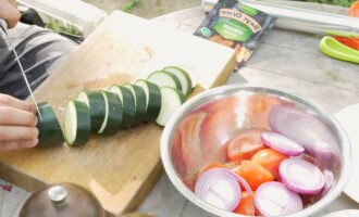 Dernæst hakkes løg og zucchini ganske groft, så de ikke hurtigt brænder på bålet. Læg alle grøntsagerne i en beholder med krydderier, bland godt og lad det marinere i et par timer.