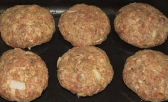 Place a small bowl of water next to the work area. Wet your hands and take a medium-sized piece of minced meat. We form the blank. We take out a baking sheet, spread paper on it and grease it with oil. Lay out the cutlets.