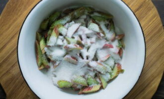 Meanwhile, cut the rhubarb into small pieces, place in a bowl, mix with sugar and leave for a couple of minutes to allow the vegetable to release its juice. Lightly crush the rhubarb with your hands. Then place the mixture in a colander to allow the juice to drain into a separate container, which will be needed later. 