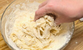 After this, knead the dough. We begin to knead with a spoon until it reaches the desired density. Then, when it thickens and its consistency becomes thicker, knead it with your hands. You can wet your hands: this will prevent the dough from sticking. 