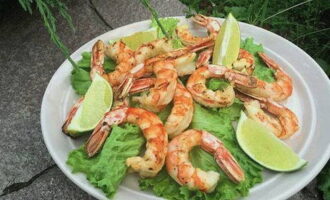 Place the finished langoustines on a serving plate with lettuce leaves. Decorate the dish with lime wedges and serve. Bon appetit!