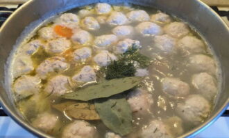 Add chopped herbs and bay leaves to the soup. Cook the dish over low heat for another 15 minutes.