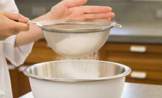 Pour the flour sifted in advance into the mixture little by little and mix well until the dough acquires the consistency of thick sour cream. 