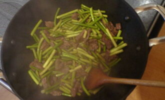 Pour vegetable oil into the frying pan. Cut the meat into thin strips and fry over high heat for 2-3 minutes. Then add the garlic arrows and fry for another 3 minutes.