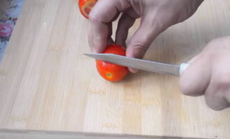 Bagaimana untuk membuat tomato masin yang cepat masak dengan bawang putih dan herba? Pilih tomato yang lebih padat dan bilas dengan air yang mengalir. Lap dengan tuala dapur dan potong bahagian atas setiap buah. Dengan cara ini pulpa tomato akan lebih tepu dengan perapan dan jeruk. 