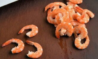 How to cook shrimp in batter at home? Take king prawns, it is better to choose the larger ones. Small shrimp become too tough when fried for a long time. Boil water in a saucepan and cook them for about 2-3 minutes. After this, drain them in a colander and cool. If you bought boiled-frozen shrimp, this will speed up the preparation. In this case, simply defrost them by leaving them at room temperature for several hours. Peel the cooled shrimp from the shell, leaving only the tails. Remove the heads as well.