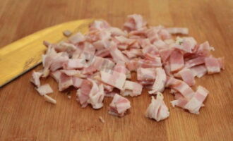 Bacon must be cut into small squares. Their size should not exceed 1 centimeter. Place the frying pan on the stove and let it warm up. Lubricate it with vegetable oil. You can also use butter. 