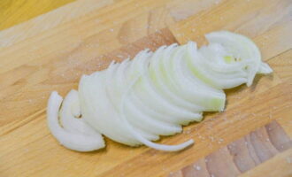 Meanwhile, peel the onion and cut into thin half rings.