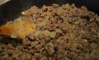 We cut the onion into arbitrary shapes: you can chop it, or you can cut it into oblong slices. Take a frying pan, moisten it with vegetable oil and put the already chopped onion on it. Fry for a few minutes over medium heat. Add minced meat, salt and spices to the onion. Mix well and fry for 5 minutes.