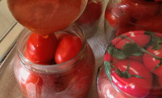 Efter 15 minutter, dræn vandet fra glasset. Hæld 1 spiseskefuld 9% eddike i glasset. Tilsæt varm puré til tomaterne. Læg glassene i en bred gryde, dæk bunden med et håndklæde, hæld vand op til bøjlerne på glassene og steriliser literglassene i 15 minutter.