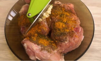 Let's start preparing the meat. After the chicken thighs have been washed well, add salt, pepper and any spices for meat. Next, add the garlic passed through the press and mix everything well. Leave the marinated meat for 30 minutes.