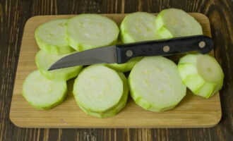 Wash the zucchini thoroughly and cut off the skin with a sharp knife. Cut the zucchini into round slices of medium thickness. Take a deep container (for example, a saucepan) and put the zucchini in it. 