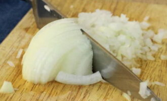 Rinse the onion in cold water. Peel off the husks and wash it again. Cut the onion into small pieces. Place it on a plate. Peel the garlic and squeeze it through a press. Add to the plate with chopped onion. 