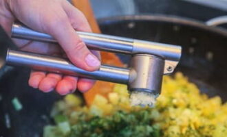 Salt and pepper the food. Here we press the garlic cloves through a press and add chopped herbs. Stir and simmer over low heat for another 20 minutes.