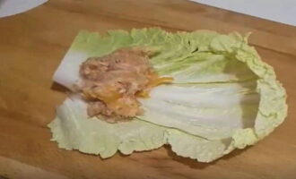 Place one leaf of Chinese cabbage. Scoop the minced meat into a spoon and place it on the base of the sheet on the hard side. Roll into a roll, tucking the edges so that the minced meat does not protrude.