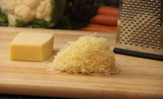 Now we need a grater. Place it on a small plate and grate the cheese.