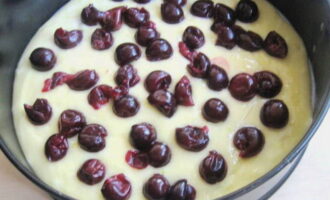 Take the dough ready for baking out of the refrigerator and cut it into two equal parts. Roll out one piece into a round shape and place it in a baking dish previously lined with parchment paper. Place a layer of cherries on the dough. Sprinkle it with almonds. 