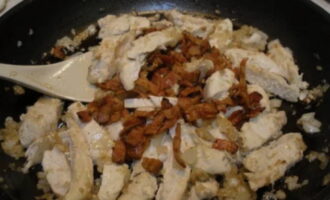 Once again, heat the pan in which we previously fried the bacon. Now we need to grease it with butter. Place onion and garlic in the pan. Fry the ingredients until golden brown. After that, add chicken and bacon to them. Fry everything for 1-2 minutes. 