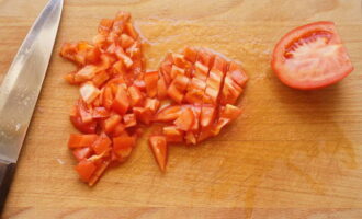 Também cortamos os tomates em cubos. Se desejar, você pode escaldá-los com água fervente e retirar a casca.