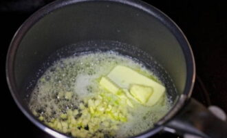 Let's start with the sauce. To do this, place butter and finely chopped garlic in a saucepan preheated over low heat.