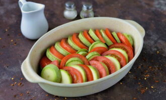 Unte uma assadeira com óleo vegetal e coloque a abobrinha e o tomate, alternando. Adicione sal e pimenta a gosto.