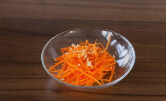 Wash the carrots, peel and grate into strips. Peel the garlic, chop it and mix with carrots.