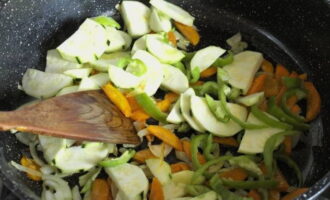 To stew the stew, take a deep frying pan. Heat vegetable oil in it and fry chopped onions and carrots over high heat. Then add sliced ​​zucchini and sweet pepper to them and fry for 7 minutes, stirring occasionally with a spatula.