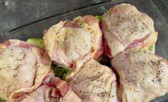 Wash the chicken thighs, rub with salt and spices. Place the meat on top of the vegetables.